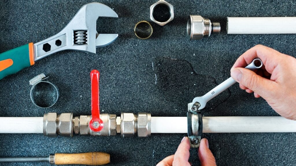 Plumber repairing a pipe valve with an adjustable wrench in Seminole