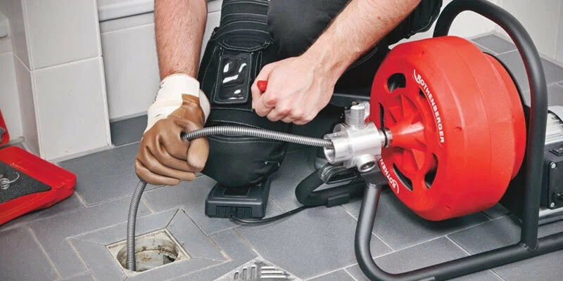 Plumber using a drain-cleaning machine in Seminole