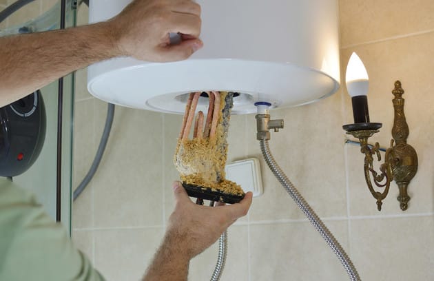 Technician removing mineral buildup from a water heater in Seminole