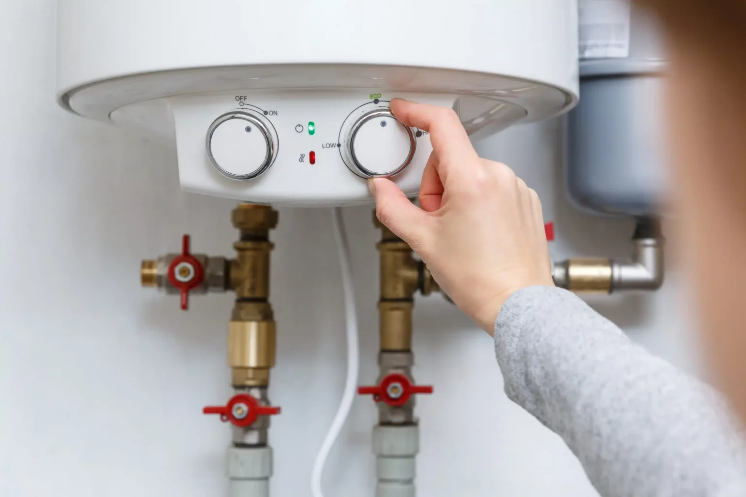 Homeowner adjusting the temperature controls on a water heater in Seminole
